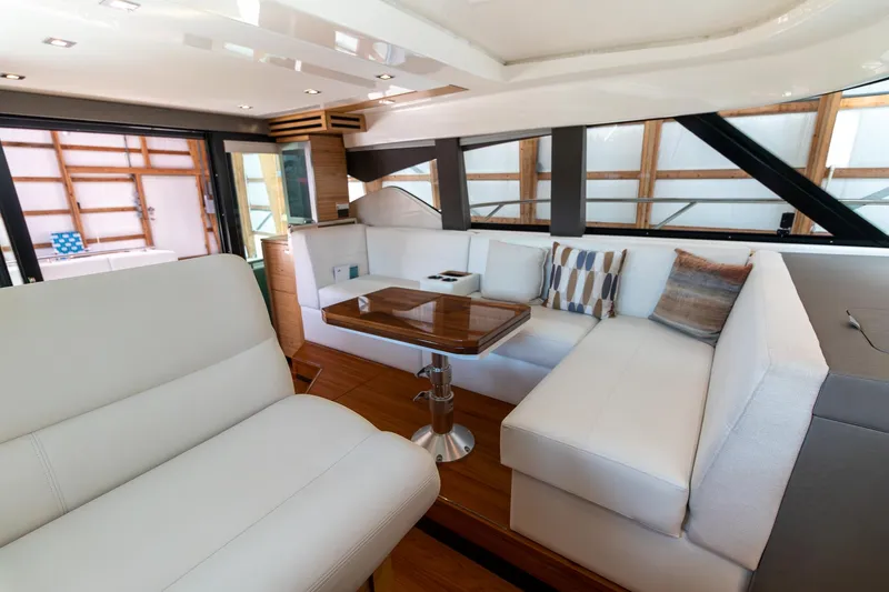 Slide: The Image of 2023 Tiara Yachts C44 Coupe interior with elegant white seating and wooden table. - 18