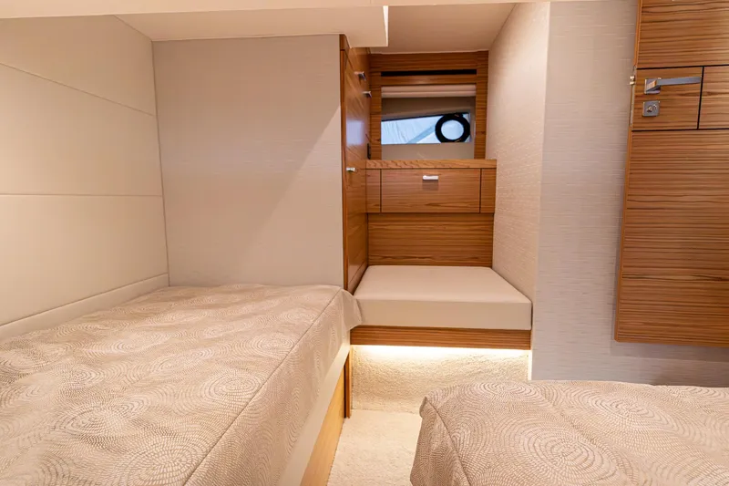 Slide: The Image of 2023 Tiara Yachts C44 Coupe cabin interior with twin beds and wooden cabinetry. - 34