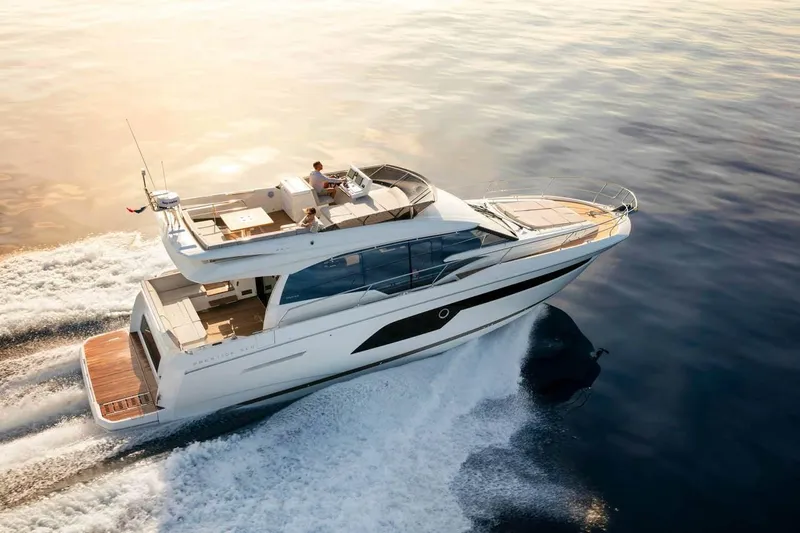 Slide: The Image of 2024 Prestige 520 Fly yacht cruising on calm waters at sunset. - 1