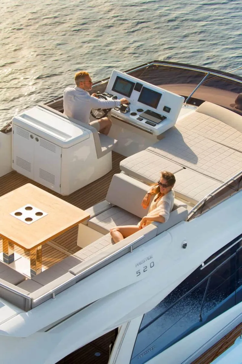 Slide: The Image of 2024 Prestige 520 Fly yacht with people relaxing on the deck, cruising on calm waters. - 13
