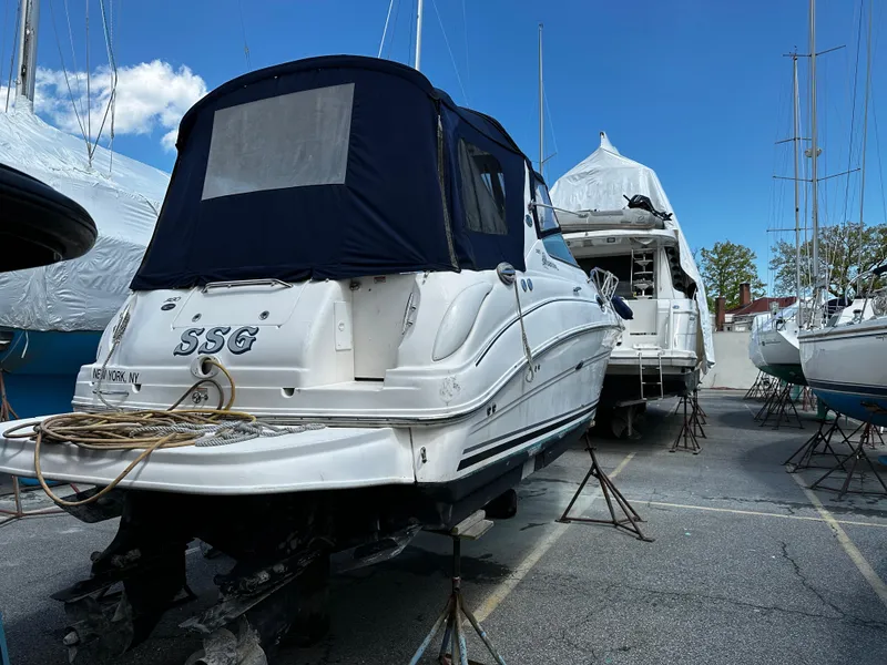 Slide: The Image of 2006 Sea Ray 280 Sundancer boat on stands, covered, in a marina. - 1