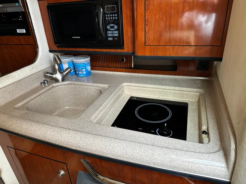 Slide: The Image of Compact kitchen area in a 2006 Sea Ray 280 Sundancer boat with sink and stove. - 17