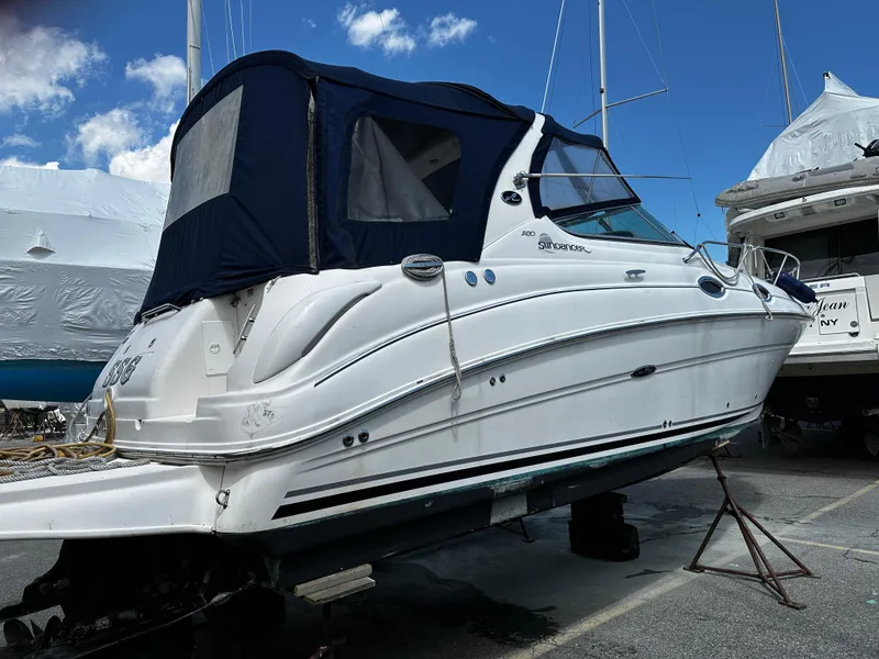 Slide: The Image of 2006 Sea Ray 280 Sundancer boat on dry dock with blue canopy. - 2