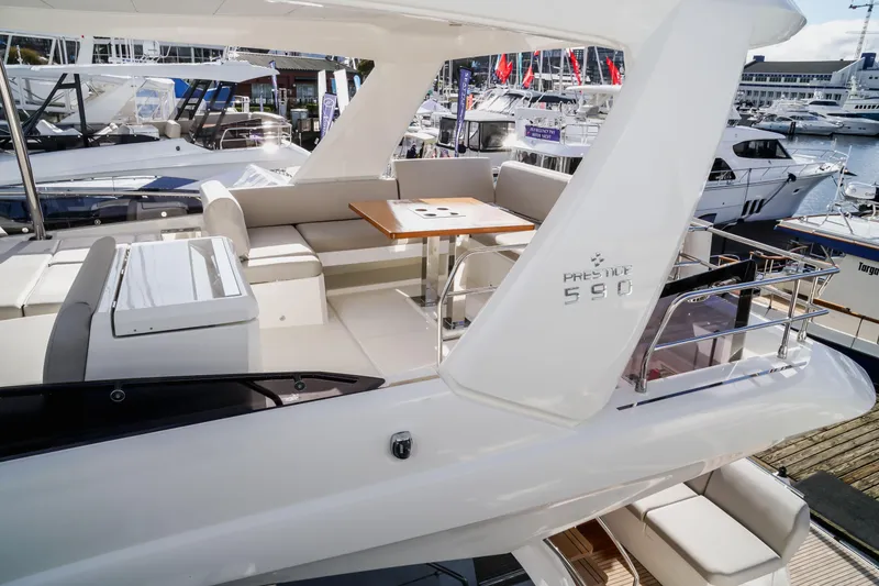 Slide: The Image of Luxurious 2025 Prestige 590 yacht with elegant seating and dining area at a marina. - 18