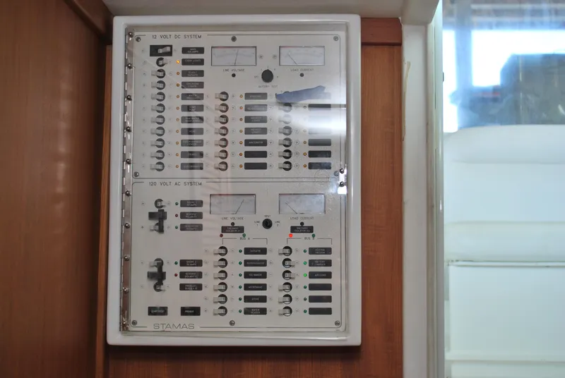 Slide: The Image of Electrical panel on a 2005 Stamas 370 Express boat, featuring various switches and meters. - 26