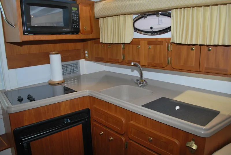Slide: The Image of 2005 Stamas 370 Express boat kitchen with wooden cabinets, microwave, and sink. - 38