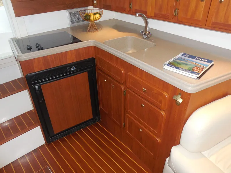 Slide: The Image of 2005 Stamas 370 Express yacht kitchen with wooden cabinets, sink, and compact fridge. - 39