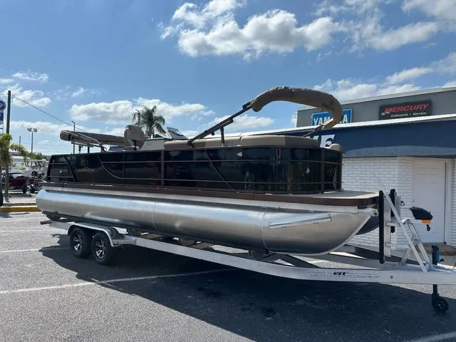 Slide: The Image of 2025 Veranda Relax VLC VR25VLC pontoon boat on trailer, parked outdoors under blue sky. - 4
