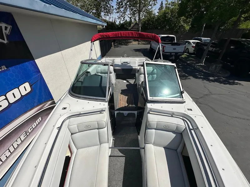 Slide: The Image of 1991 Cobalt Condurre 222 boat with open bow seating and red canopy, parked outdoors. - 32