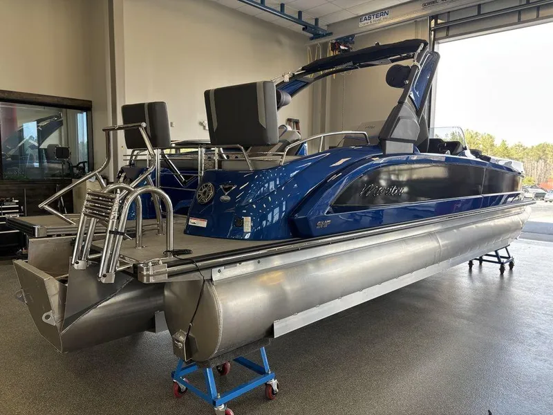 Slide: The Image of 2024 Manitou 25 XT SRS SHP pontoon boat in showroom, featuring sleek blue design. - 3