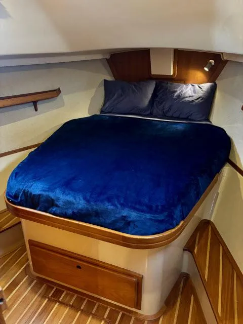 Slide: The Image of 2008 Island Packet 370 cabin with blue bedding and wooden accents. - 12