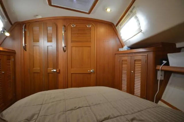 Slide: The Image of Interior cabin of 2008 Island Packet 370 sailboat with wooden cabinetry and cozy bedding. - 16