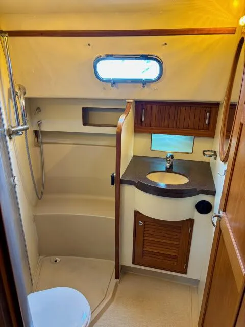 Slide: The Image of 2008 Island Packet 370 yacht bathroom with shower, sink, and wooden cabinetry. - 17