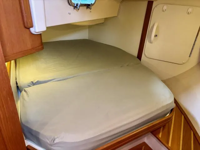 Slide: The Image of Cozy cabin bed in 2008 Island Packet 370 sailboat, featuring wooden accents and a porthole. - 20