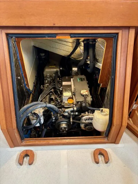 Slide: The Image of Engine compartment of a 2008 Island Packet 370 sailboat, showcasing mechanical components and wooden paneling. - 28