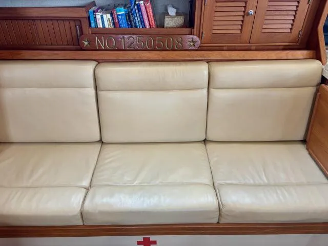 Slide: The Image of Cream leather seating in 2008 Island Packet 370 sailboat interior with books and wooden cabinetry. - 3