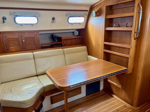 Slide: The Image of Interior of 2008 Island Packet 370 sailboat with wooden table and beige seating. - 4