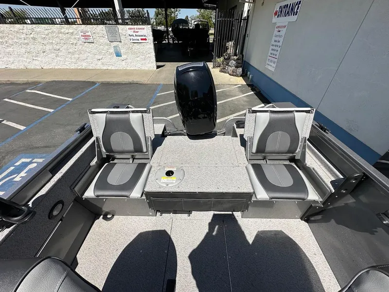 Slide: The Image of 2017 Crestliner 1600 Vision boat interior with seating and motor, parked outdoors. - 14