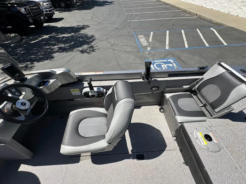 Slide: The Image of 2017 Crestliner 1600 Vision boat interior with seating and steering wheel in a parking lot. - 16