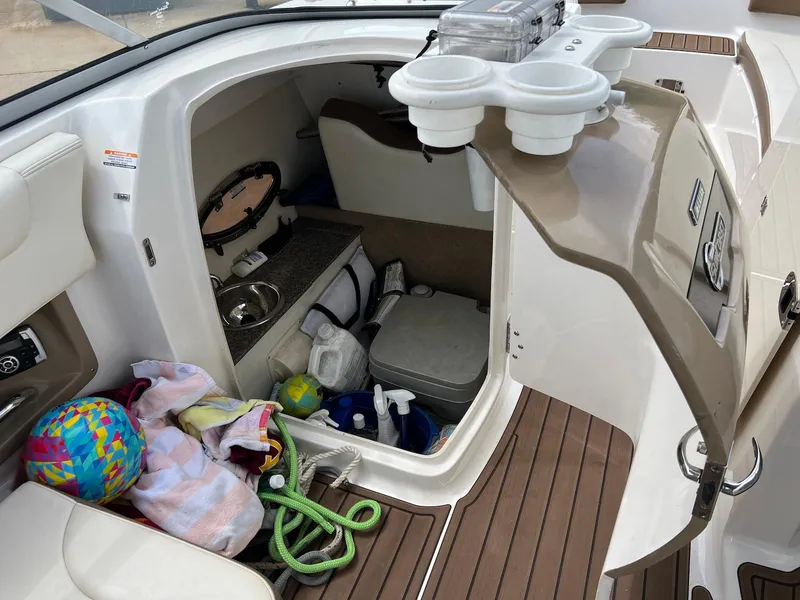 Slide: The Image of 2016 Chaparral 250 Suncoast boat interior with storage, sink, and accessories. - 12