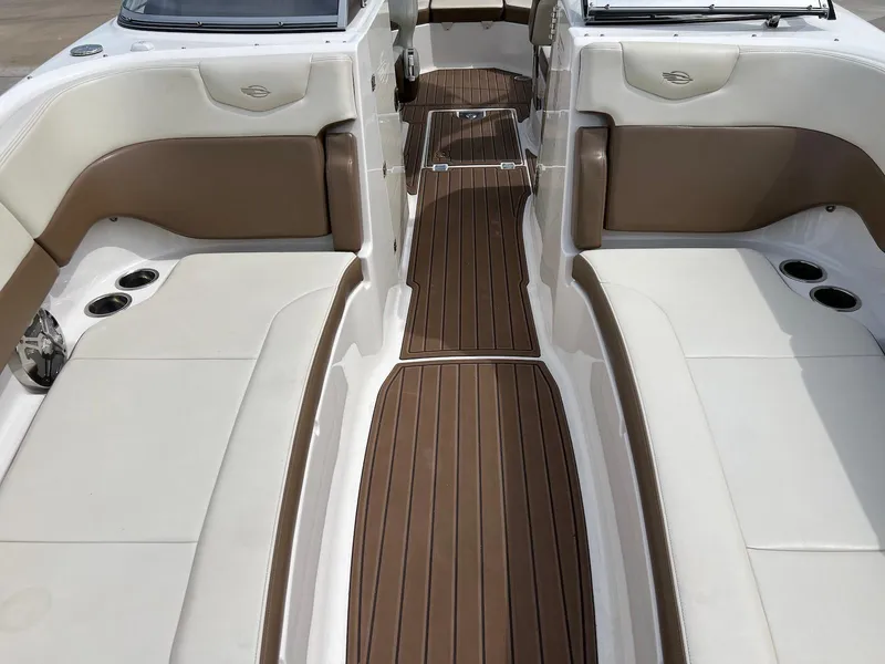 Slide: The Image of 2016 Chaparral 250 Suncoast boat interior with brown and white seating and wood-style flooring. - 16
