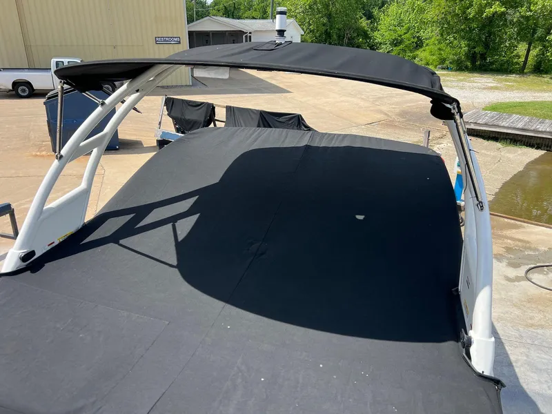 Slide: The Image of 2016 Chaparral 250 Suncoast boat with black cover and canopy, docked outdoors. - 20