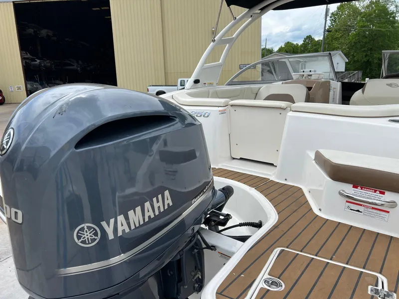 Slide: The Image of 2016 Chaparral 250 Suncoast boat with Yamaha outboard motor, docked near a warehouse. - 24