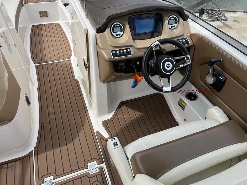 Slide: The Image of 2016 Chaparral 250 Suncoast boat interior with brown and white seating, modern dashboard, and steering wheel. - 4