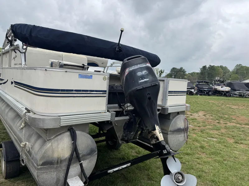 Slide: The Image of 2000 Starcraft 200 Classic pontoon boat with outboard motor on grassy field. - 12