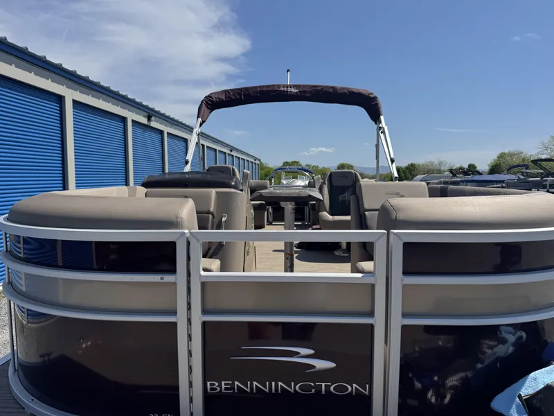 Slide: The Image of 2022 Bennington 22 SXSR pontoon boat parked near blue storage units under clear sky. - 5