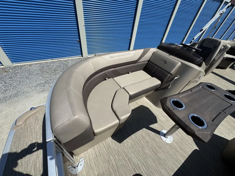 Slide: The Image of 2022 Bennington 22 SXSR boat interior with beige seating and cupholder table. - 7