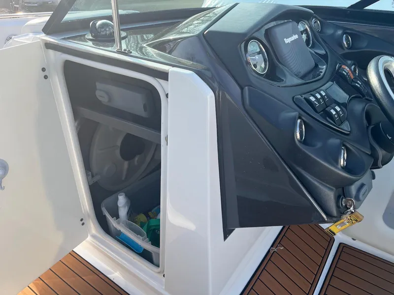 Slide: The Image of 2015 Monterey 264FSX boat dashboard with open storage compartment and wooden flooring. - 10