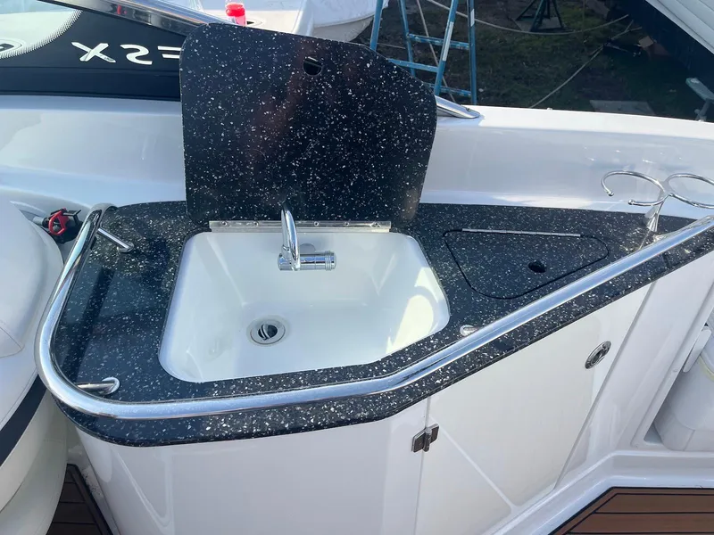 Slide: The Image of 2015 Monterey 264FSX boat sink with black speckled countertop and stainless steel fixtures. - 8