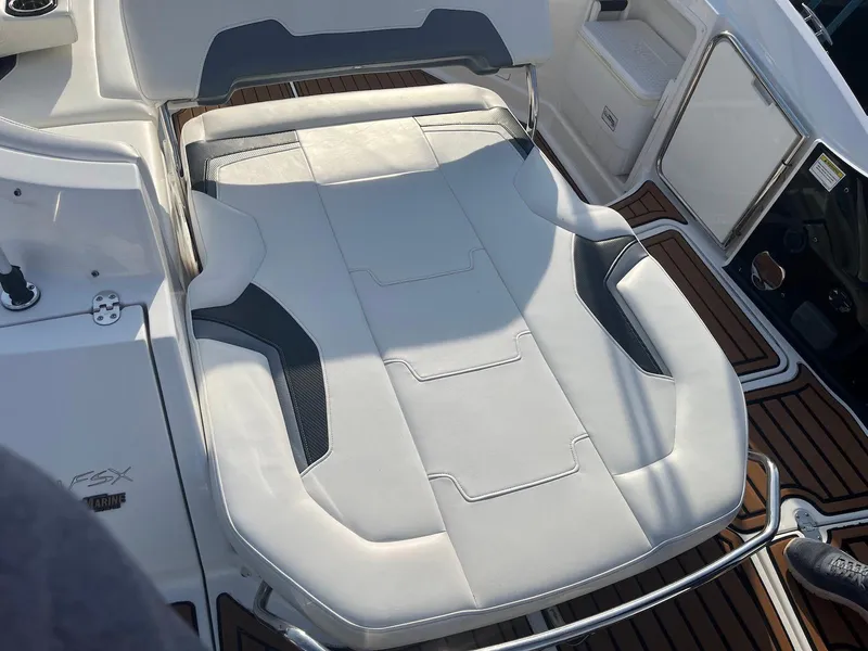 Slide: The Image of 2015 Monterey 264FSX boat interior with white cushioned seating and teak flooring. - 9