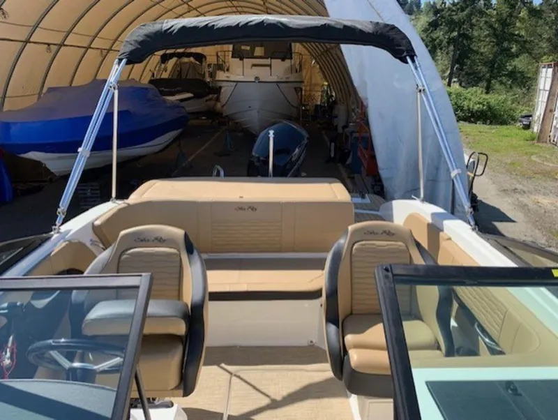 Slide: The Image of 2022 Sea Ray SPX 190 OB boat interior with tan seating, parked in a covered area. - 9