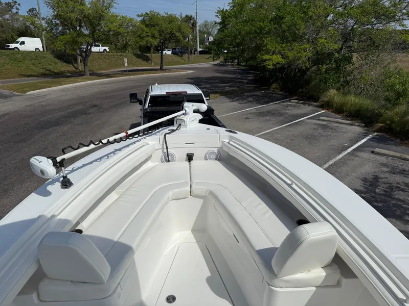 Slide: The Image of 2016 Regulator 23 boat on trailer, parked in a lot with trees and vehicles nearby. - 20