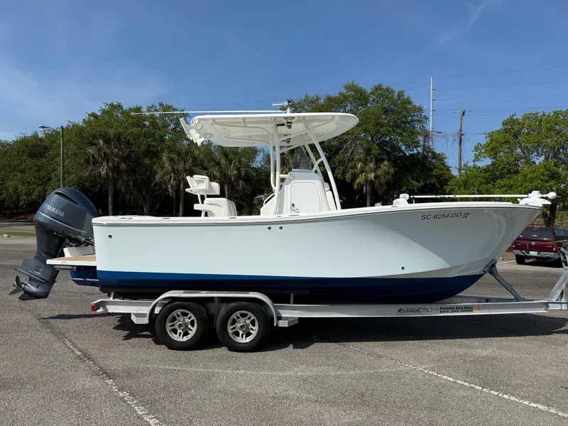 Slide: The Image of 2016 Regulator 23 boat on trailer, parked outdoors, with trees in the background. - 6