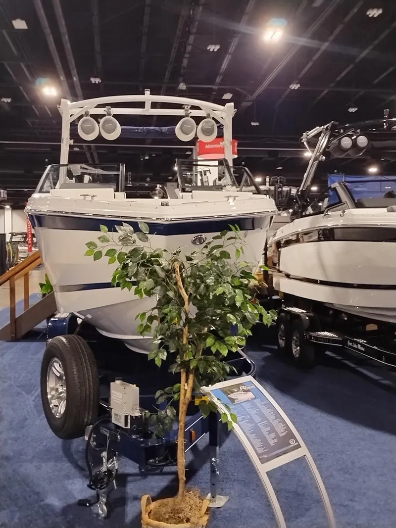 Slide: The Image of 2025 Cobalt R6 Surf boat displayed indoors, surrounded by other boats and a small potted tree. - 20