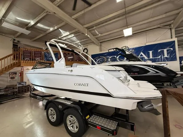 Slide: The Image of 2025 Cobalt CS22 boat on trailer in showroom, featuring sleek white design. - 1