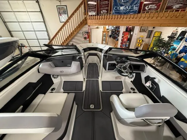 Slide: The Image of 2025 Cobalt CS22 boat interior with modern seating and dashboard in showroom. - 7