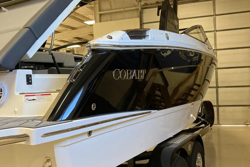 Slide: The Image of 2025 Cobalt R6 boat in showroom, sleek black and white design on trailer. - 4