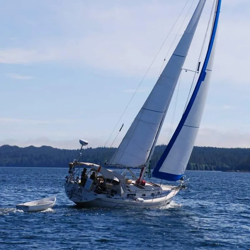 Slide: The Image of 1979 Irwin Citation 39 sailboat navigating calm waters with a small dinghy. - 0