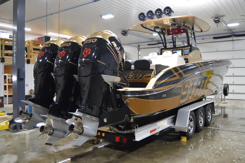 Slide: The Image of 2017 Statement 380 Open boat with triple Mercury 350 engines on a trailer in a garage. - 13