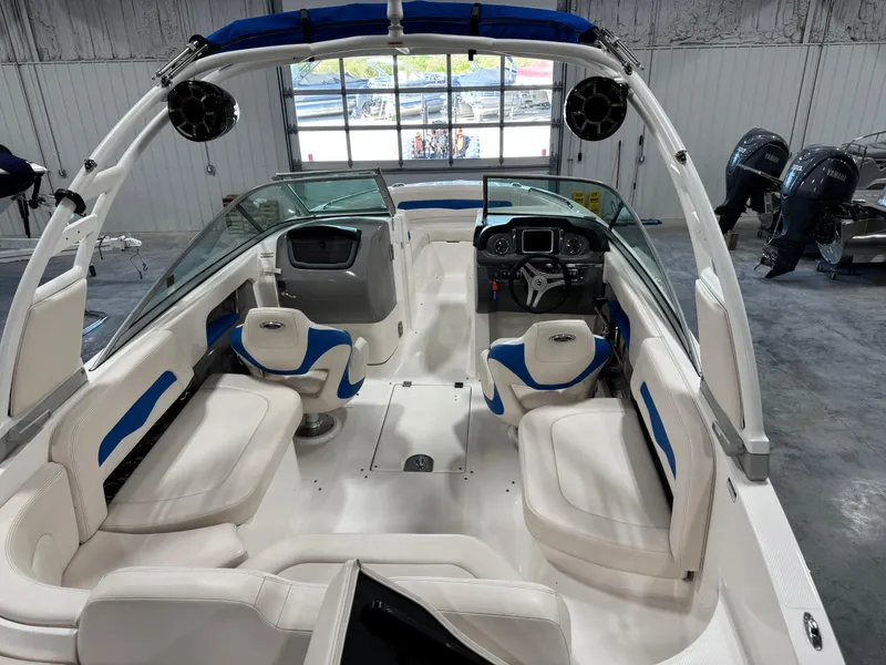 Slide: The Image of 2018 Chaparral 246 SSi Surf boat interior with white and blue seating in a showroom. - 14