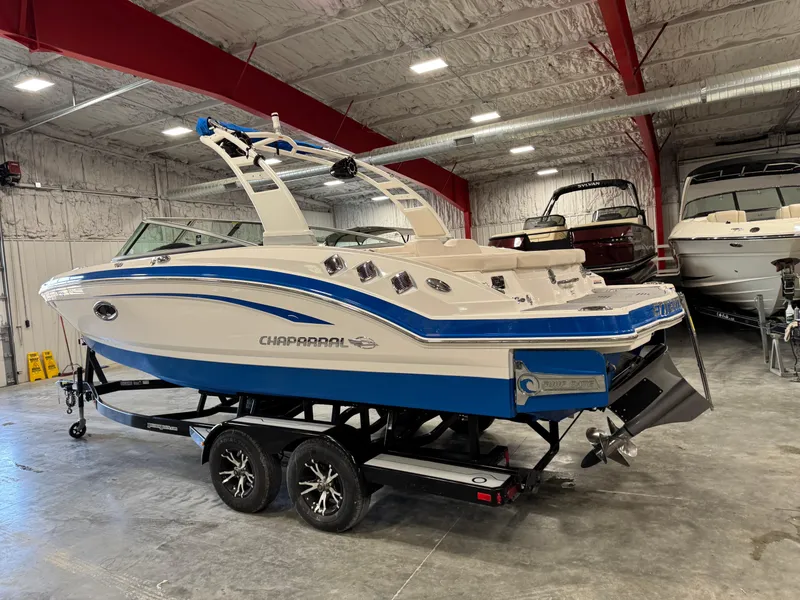 Slide: The Image of 2018 Chaparral 246 SSi Surf boat in a storage facility, featuring a blue and white design. - 4