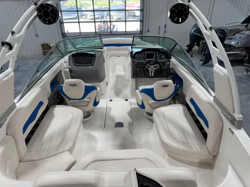 Slide: The Image of 2018 Chaparral 246 SSi Surf boat interior with white and blue seating, modern dashboard, and spacious layout. - 7