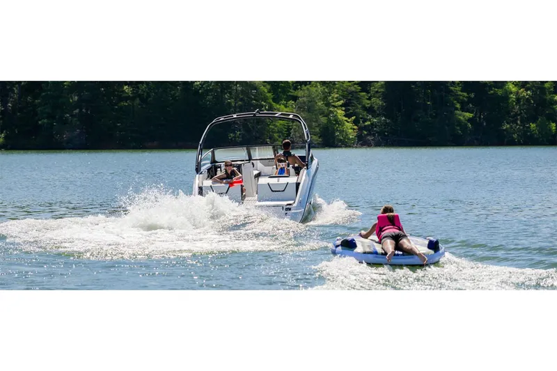 Slide: The Image of 2025 Yamaha Boats 222SE towing a person on a tube in a scenic lake. - 40