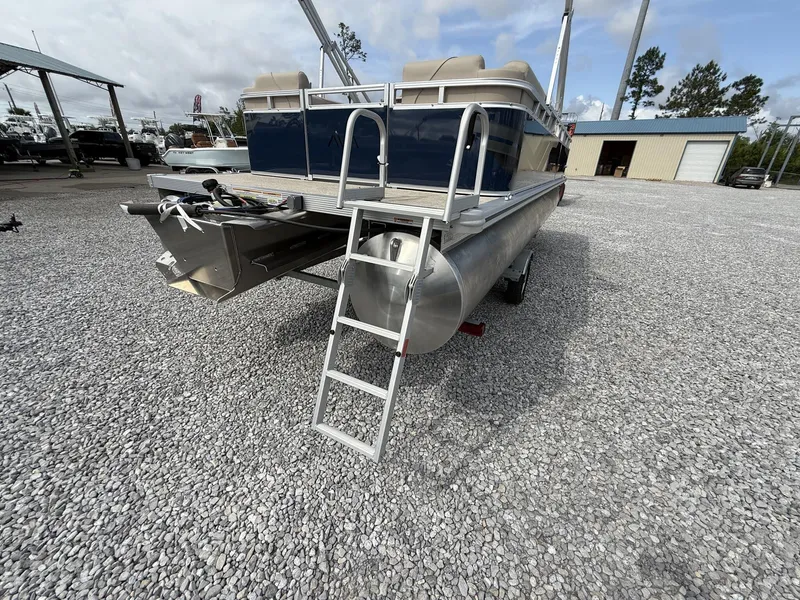 Slide: The Image of 2025 Avalon VENTURE 23 QUAD LOUNGER pontoon boat with rear ladder on gravel lot. - 7