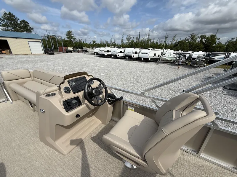 Slide: The Image of 2025 Avalon Venture 21 CRUISE boat interior with steering wheel and seating, parked near RVs. - 8