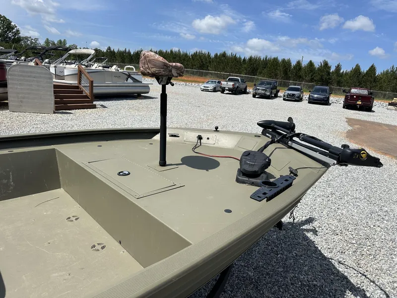 Slide: The Image of 2024 Tracker Grizzly 1860 CC boat on gravel lot with parked vehicles. - 5